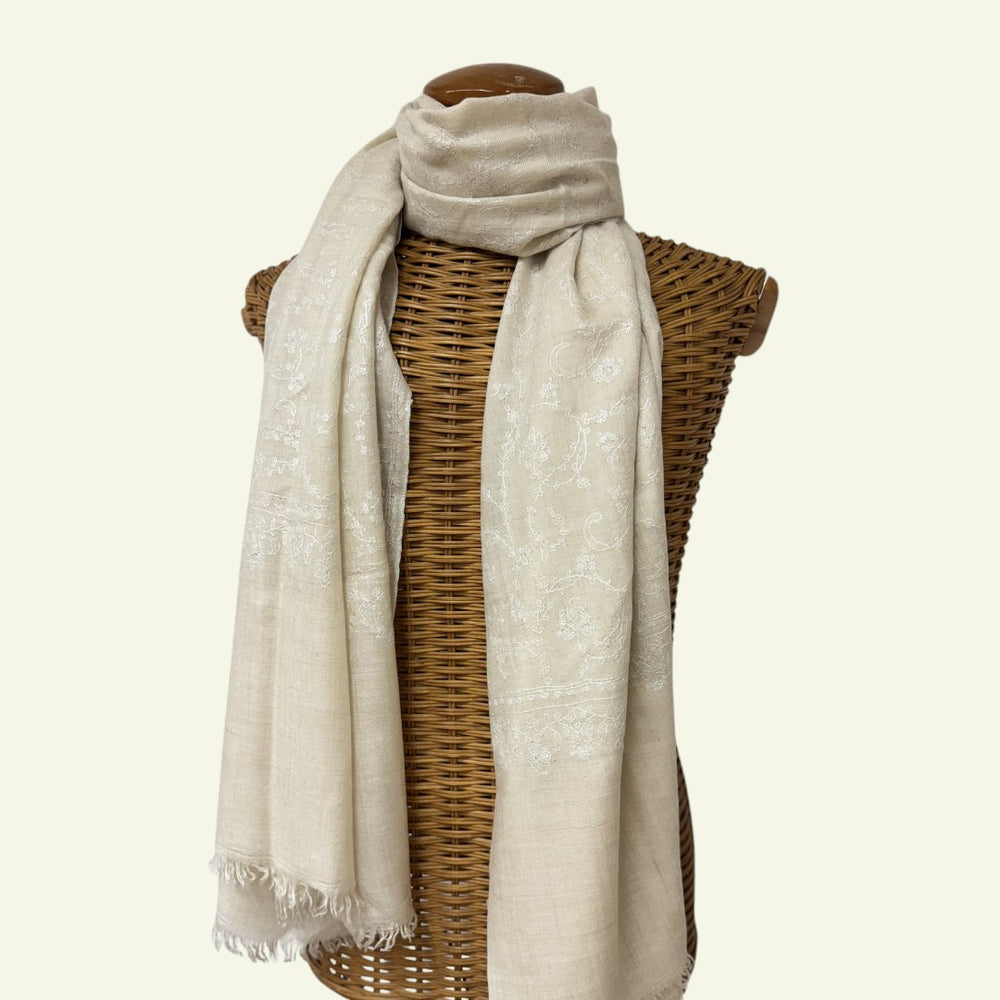 Beige scarf draped over a wicker basket on a white background
