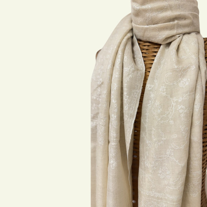 Beige scarf draped over a wicker chair on a light beige background