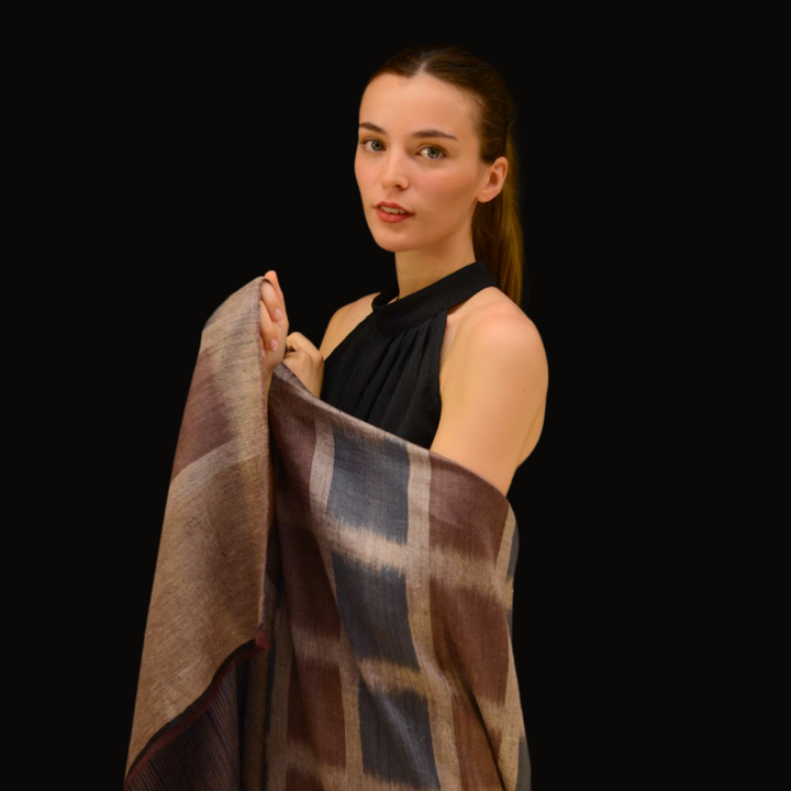 Woman holding a ikat pashmina shawl against a black background