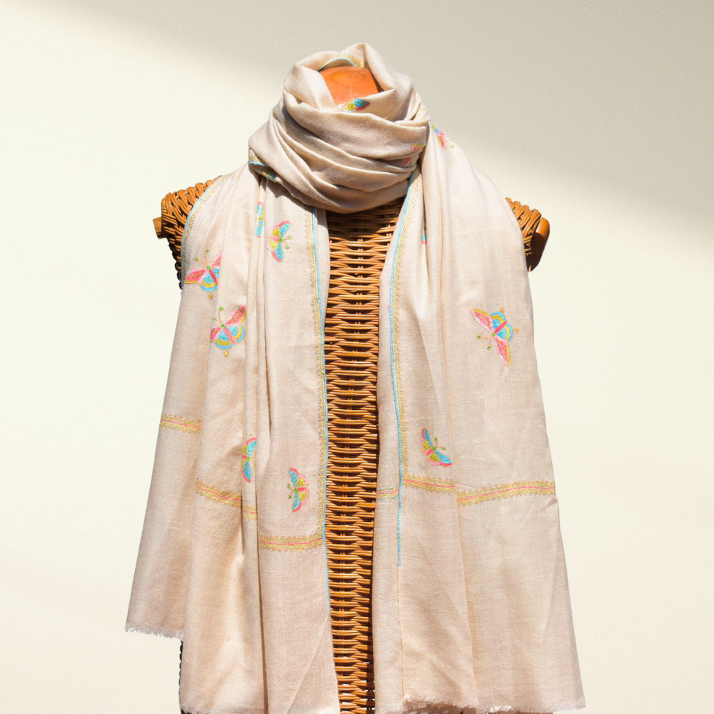 Beige pashmina shawl with butterfly embroidery on a mannequin against a neutral background