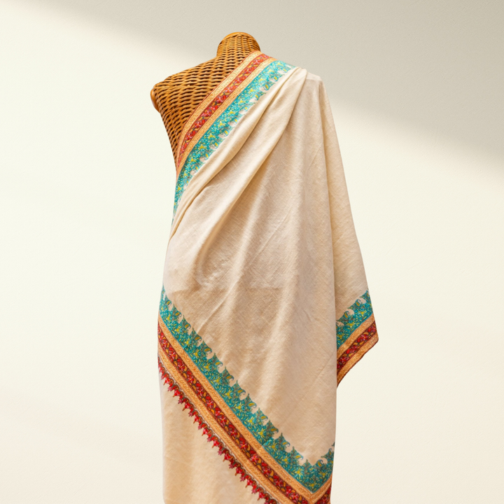 Beige pashmina shawl with colorful border on a mannequin against a neutral background