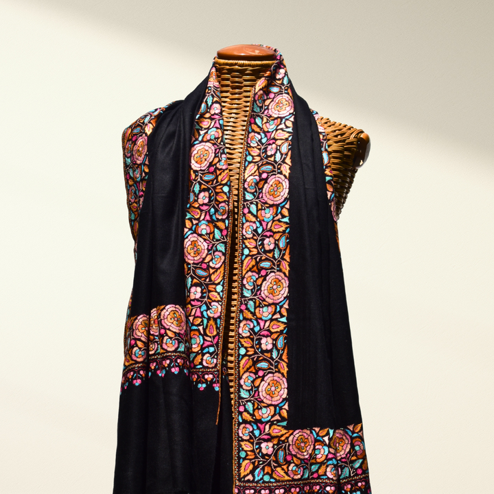 Black Pashmina shawl with colorful floral embroidery on a mannequin against a neutral background