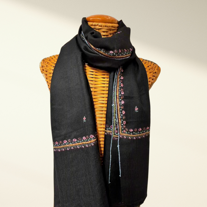 Black pashmina scarf with colorful patterns draped over a mannequin on a beige background