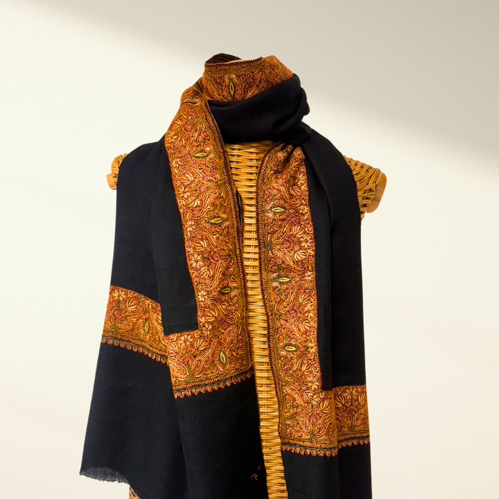 Black pashmina shawl with gold embroidery on a neutral background