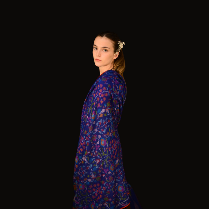 Woman wearing a blue kani pashmina shawl against a black background