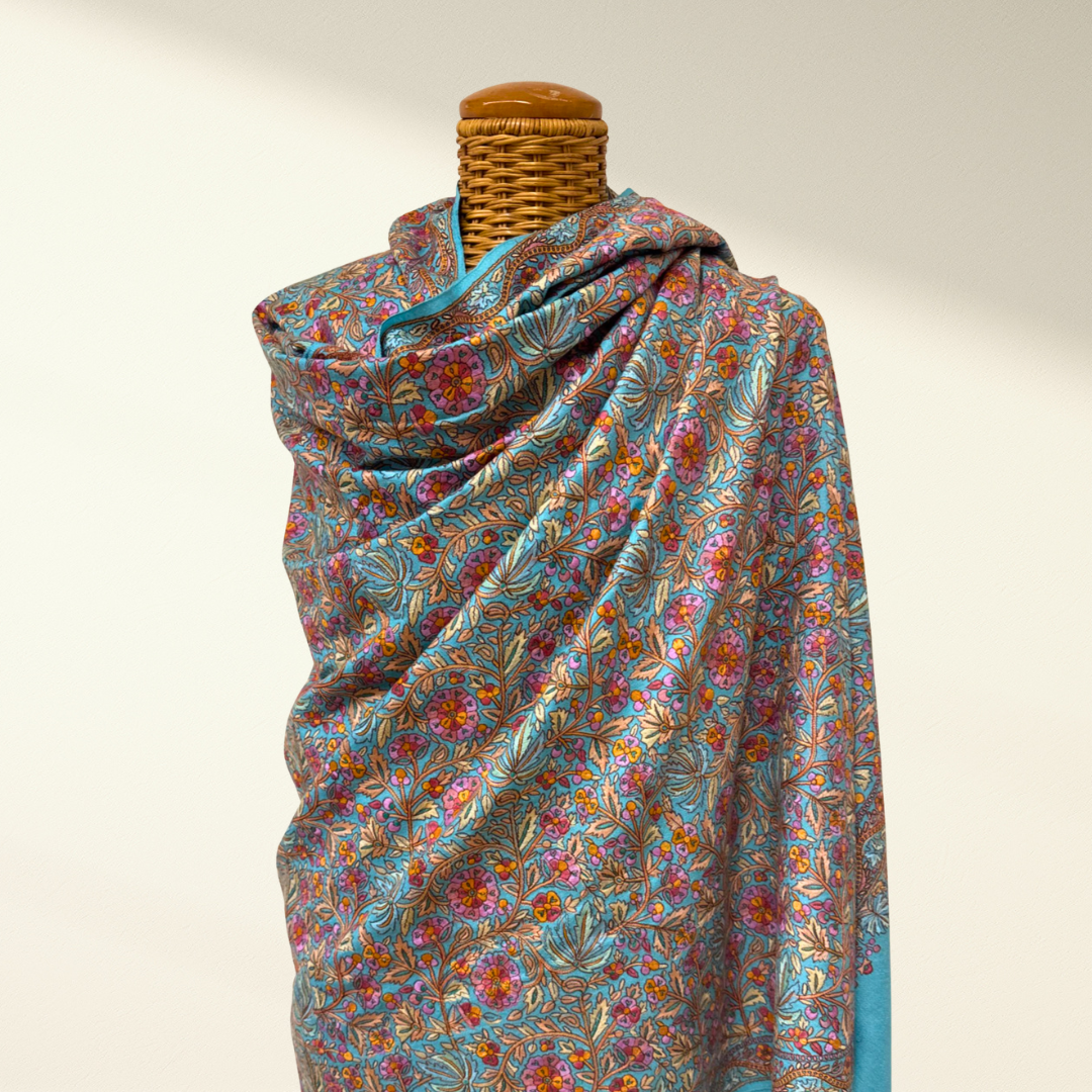 Colorful floral-patterned pashmina shawl draped over a mannequin on a plain background