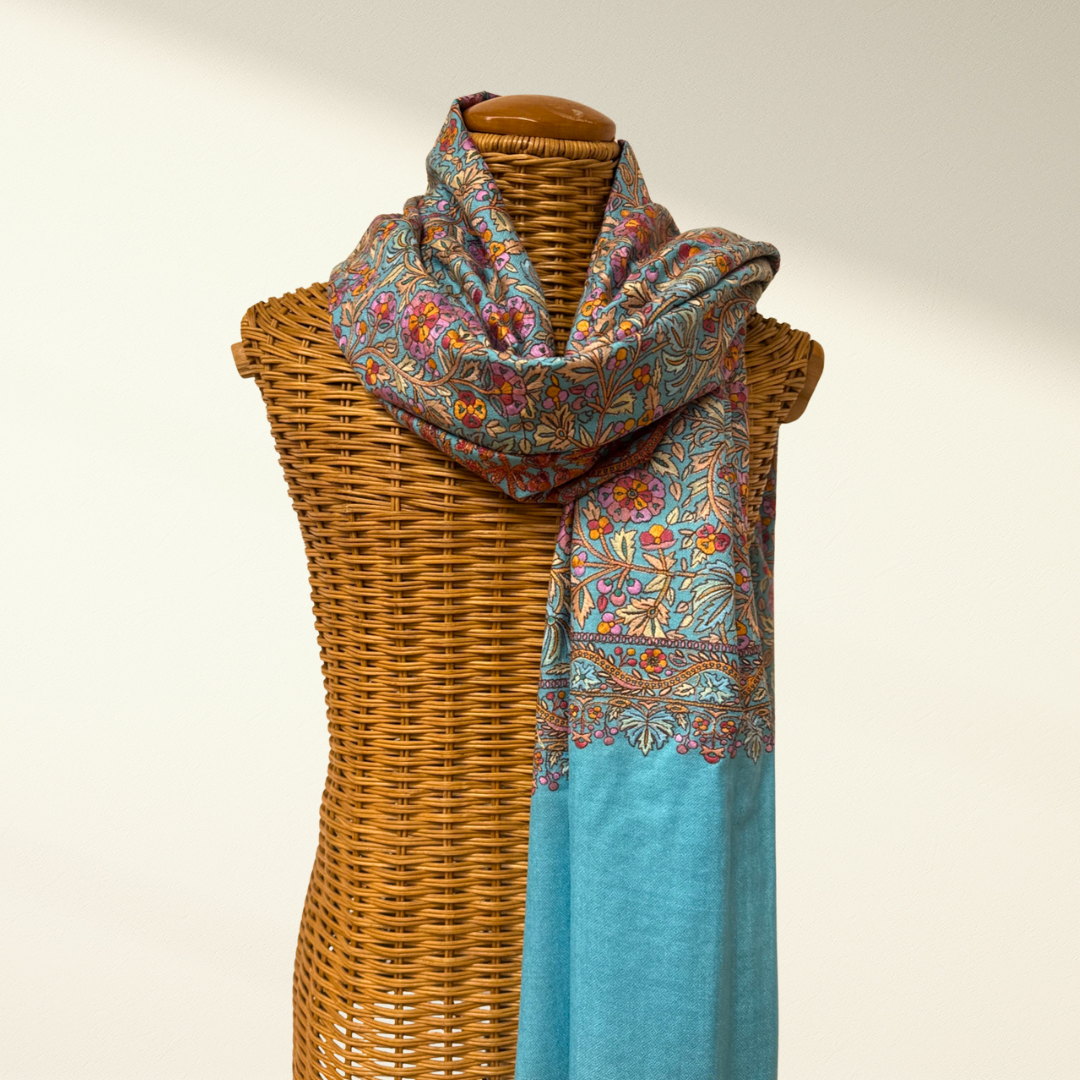 Colorful patterned pashmina scarf draped over a wicker mannequin against a plain background
