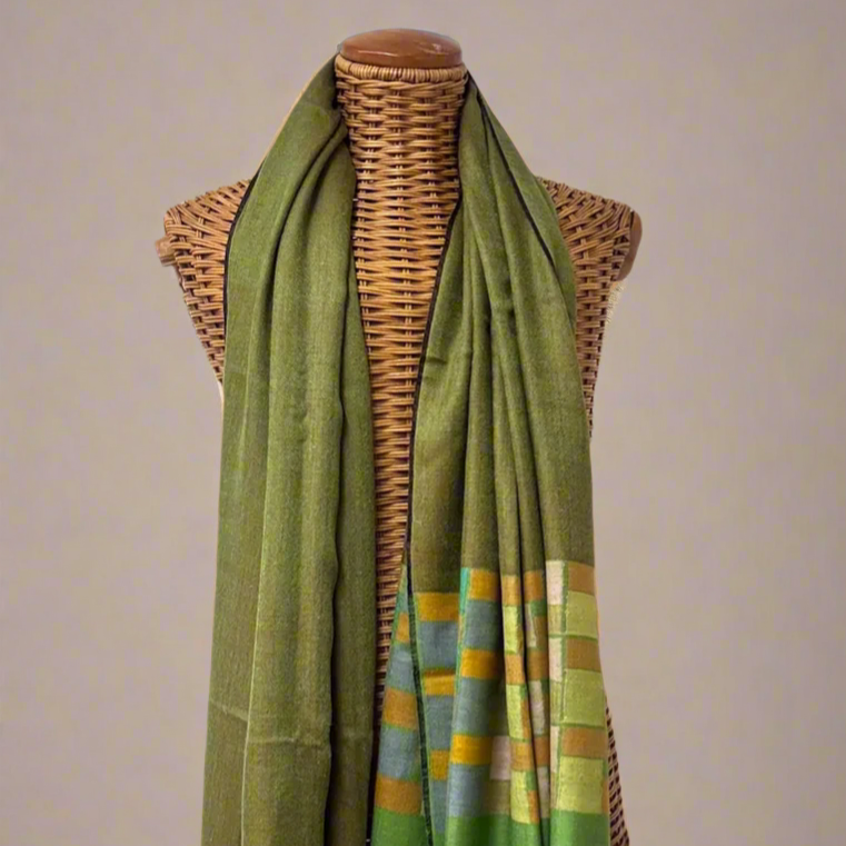 Green scarf with geometric pattern draped over a mannequin against a gray background