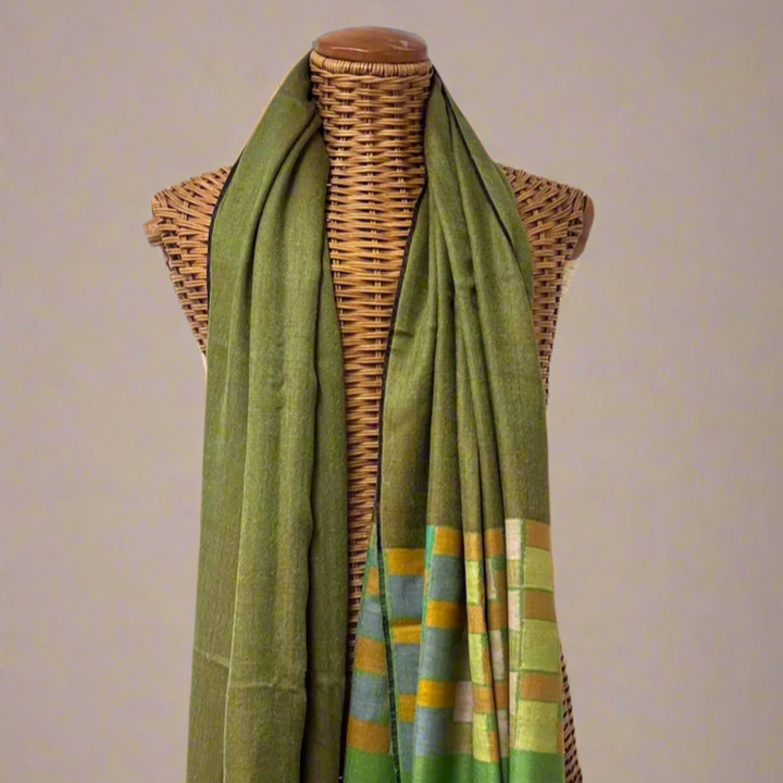 Green scarf with geometric pattern draped over a mannequin against a gray background