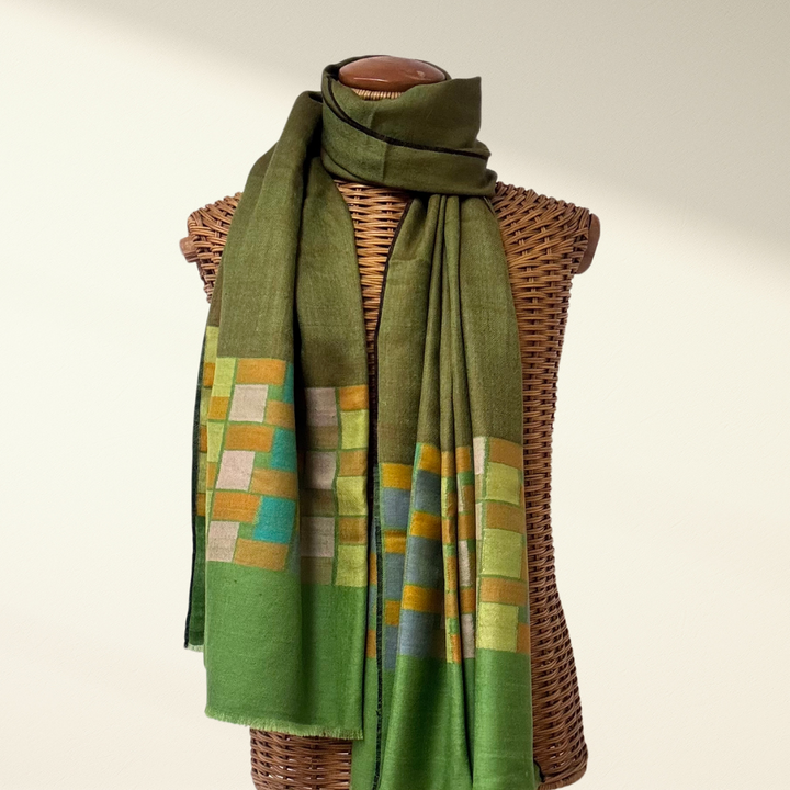 Green Pashmina Shawl Cubic with a geometric pattern draped over a wicker mannequin on a white background