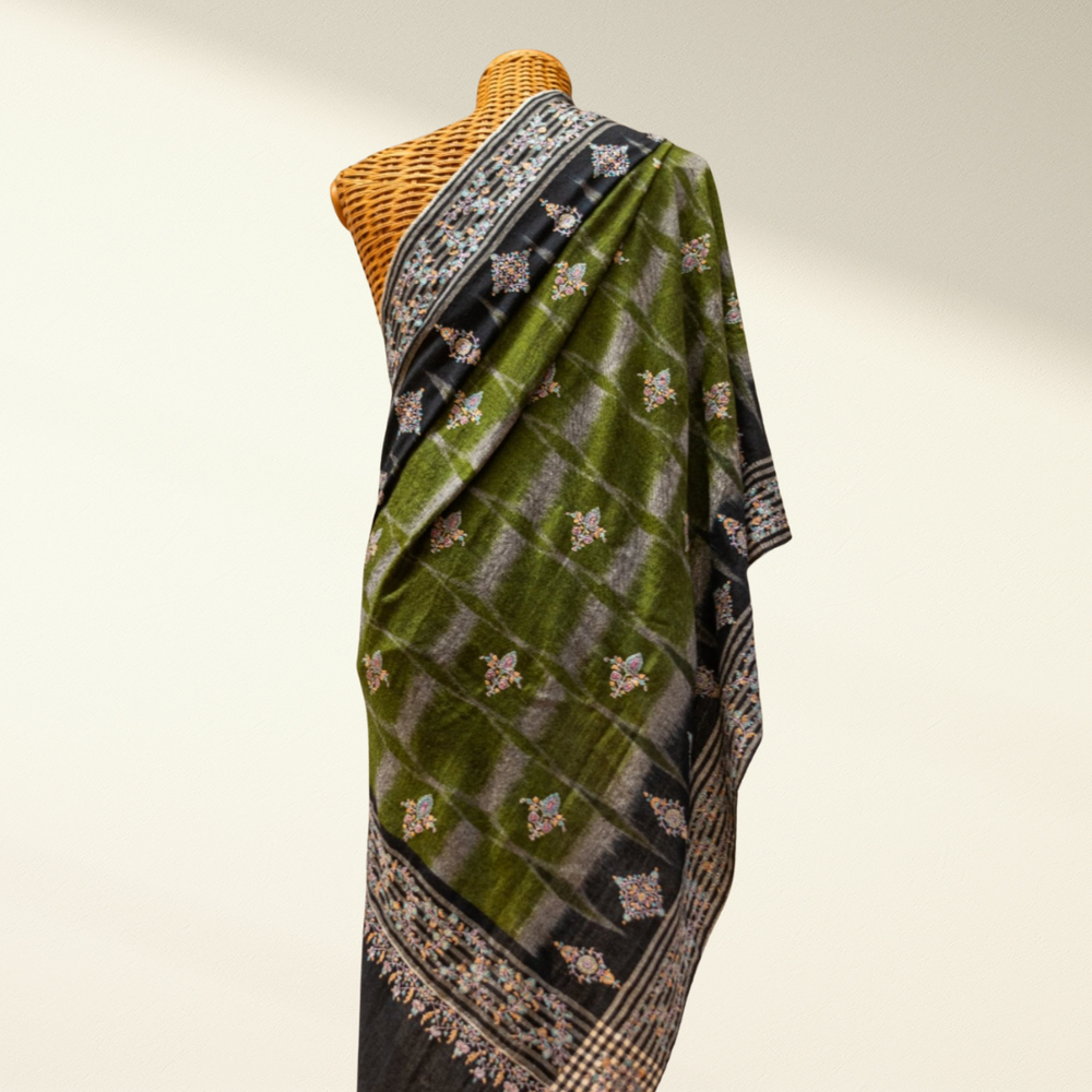 Green and black pashmina shawl with intricate patterns on a mannequin against a neutral background
