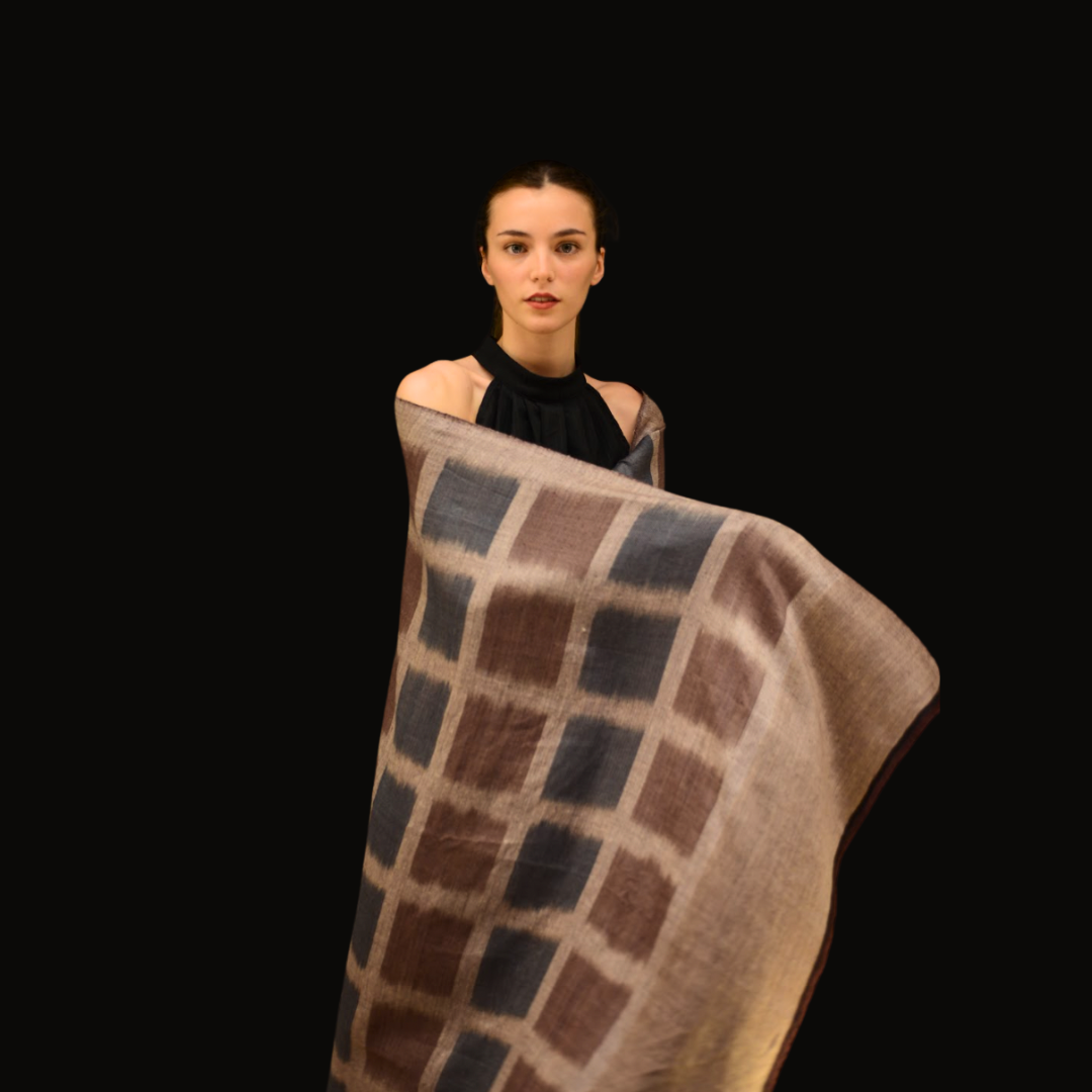 Woman holding a checkered pashmina shawl against a black background