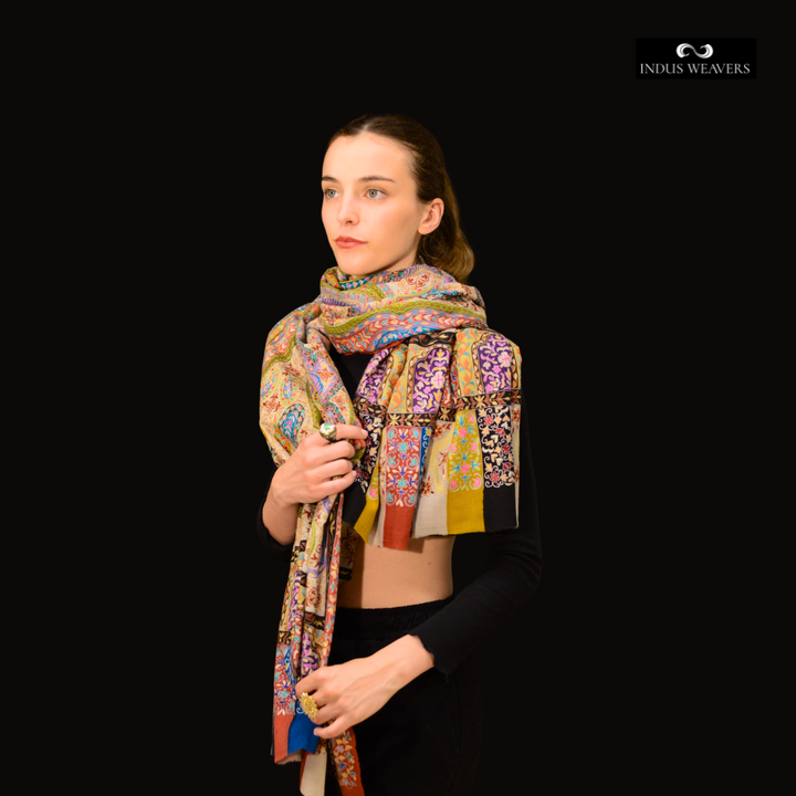 Woman wearing a colorful pashmina shawl against a black background with 'Indus Weavers' branding.