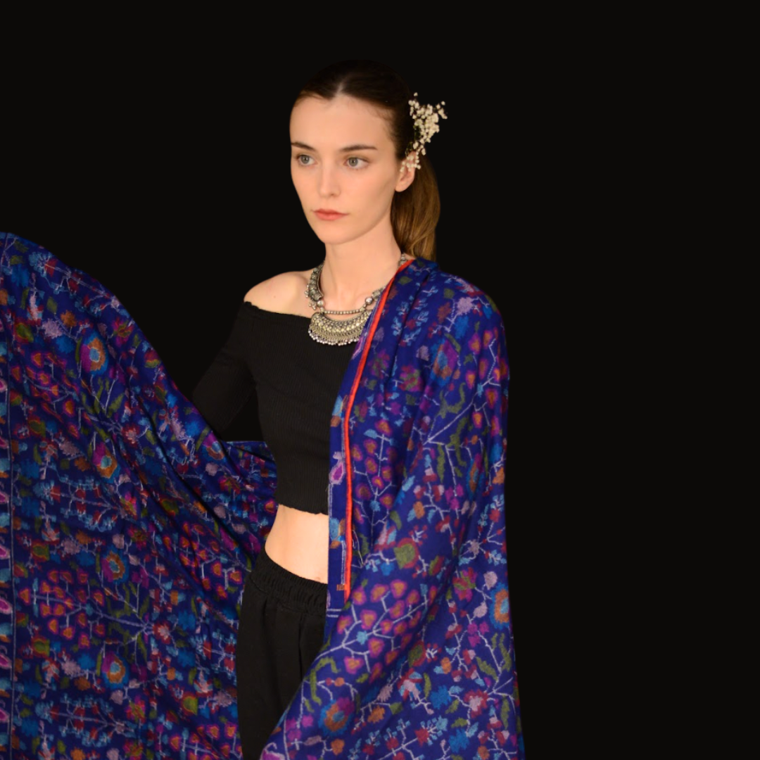 Woman wearing a colorful floral kani pashmina shawl with a black background
