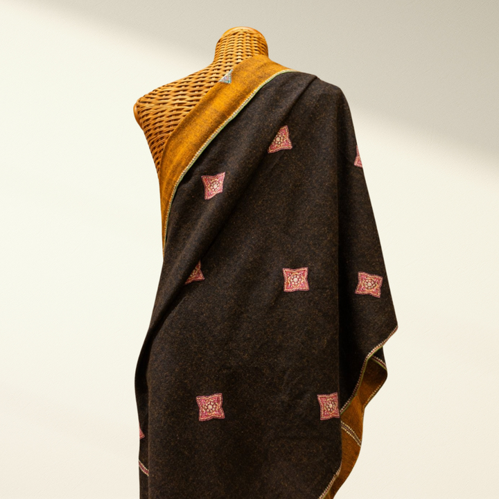 Mannequin wearing a dark brown pashmina shawl with red square patterns on a neutral background