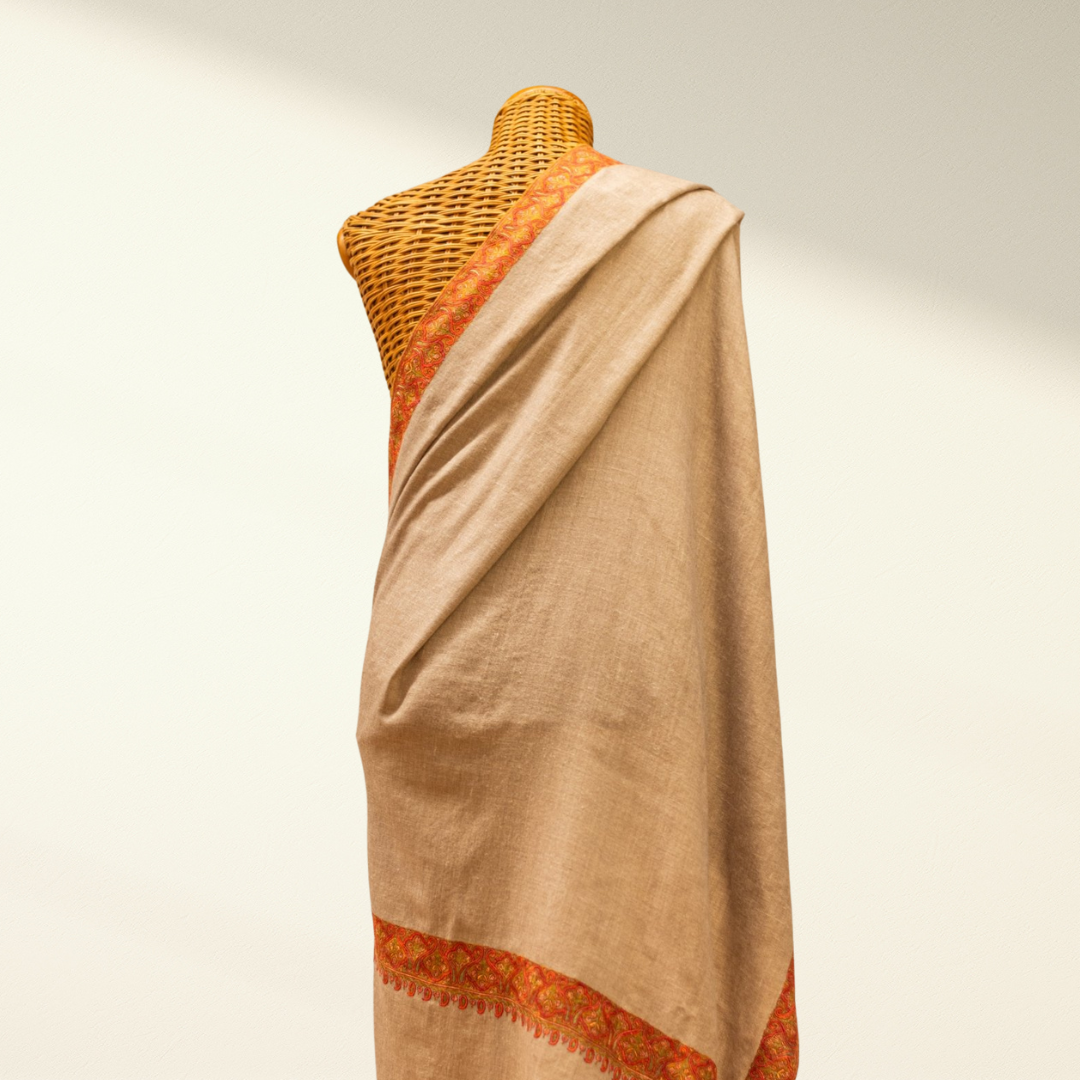 Mannequin wearing a beige pashmina shawl with orange accents on a plain background