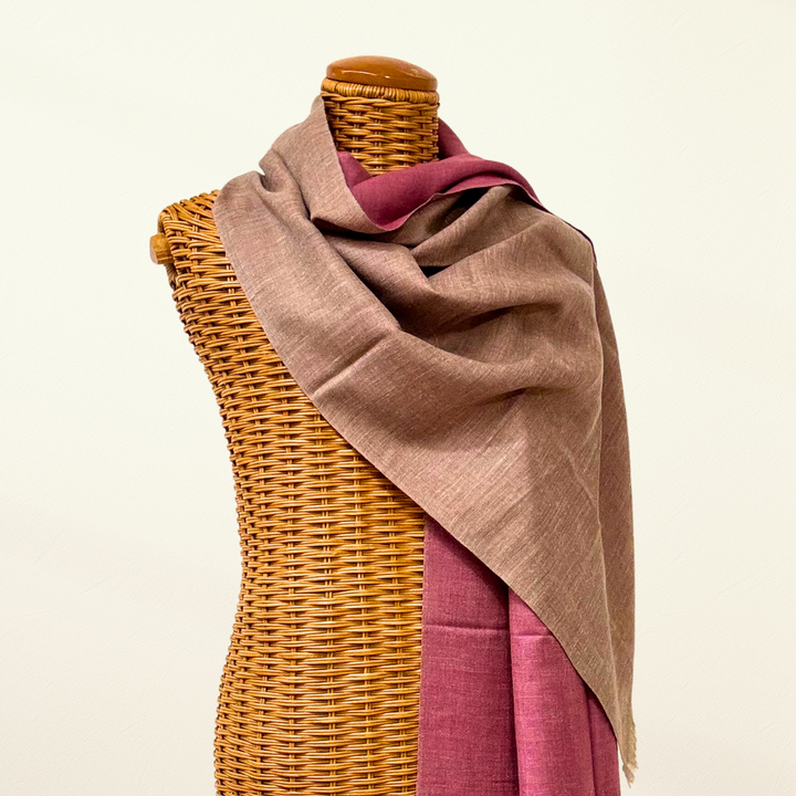 Mannequin wearing a pink pashmina scarf draped over a pink garment on a white background