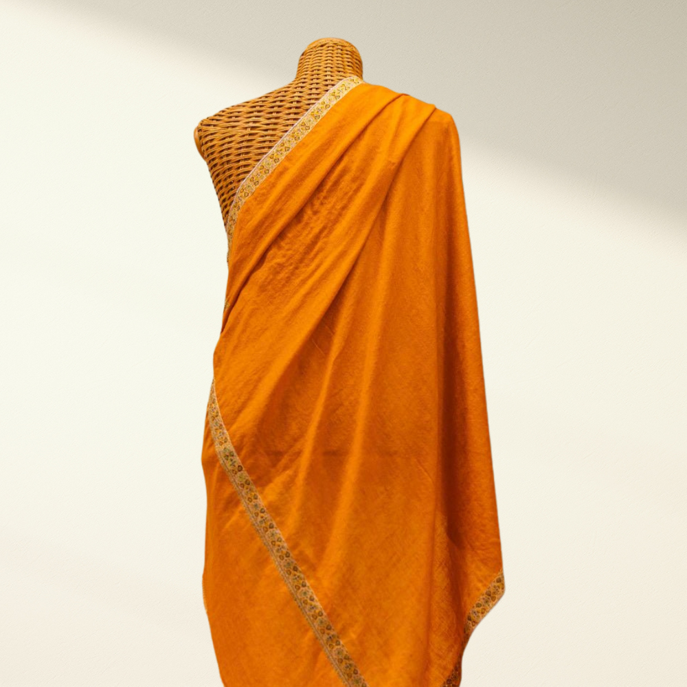 Orange pashmina shawl with a textured border on a mannequin against a neutral background
