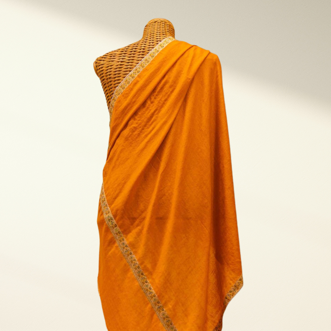 Orange pashmina shawl with a textured border on a mannequin against a neutral background