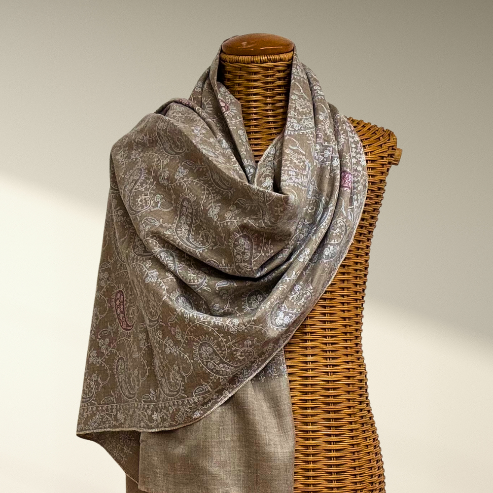 Brown pashmina scarf draped over a wicker mannequin against a neutral background