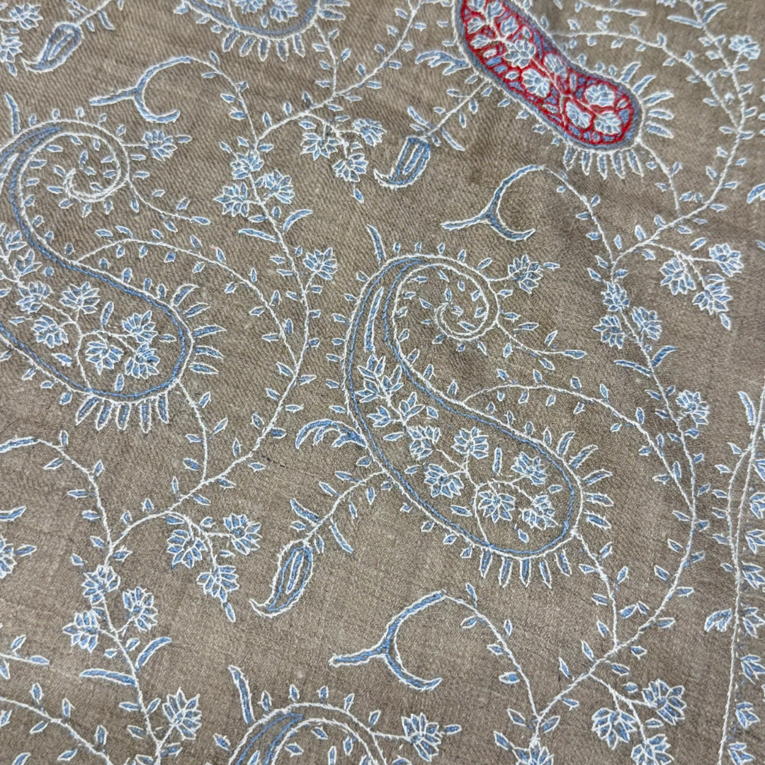 Close-up of a Pashmina with intricate paisley pattern on a beige background