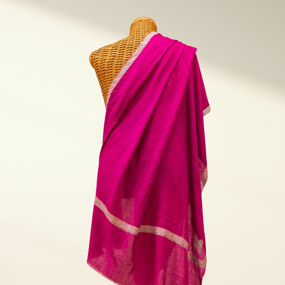 Pink pashmina shawl with white border on a mannequin against a plain background