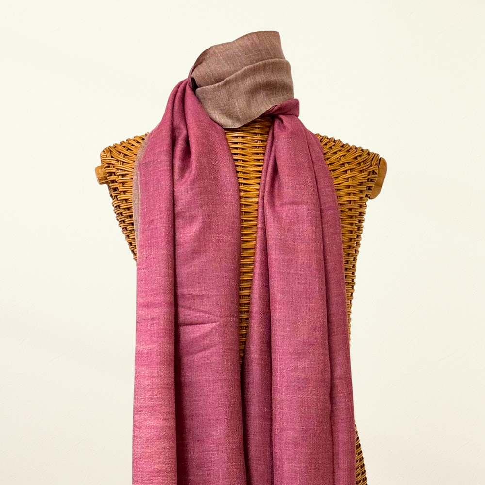 Pink pashmina scarf draped over a wicker mannequin on a beige background