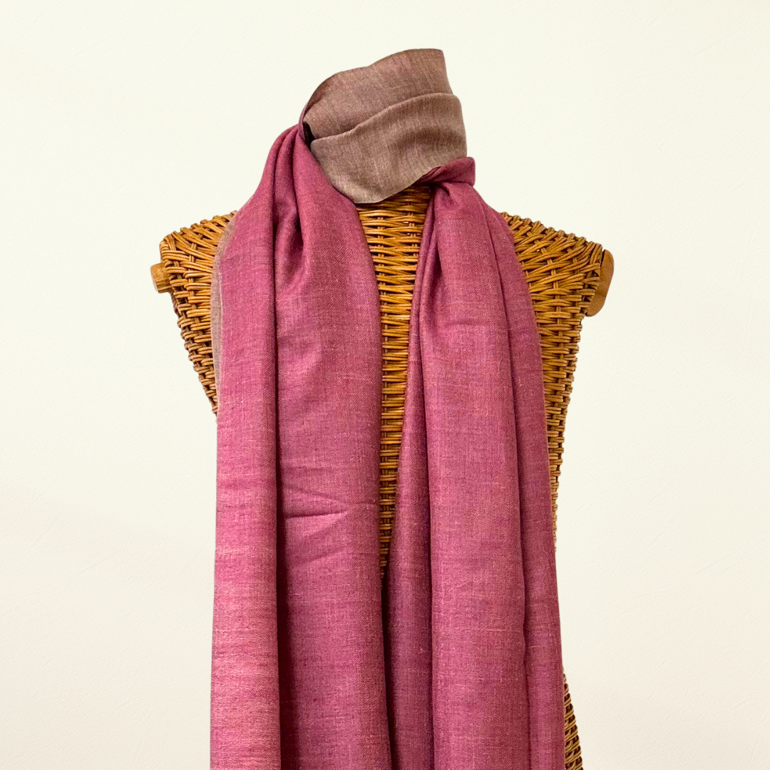 Pink pashmina scarf draped over a wicker mannequin on a beige background