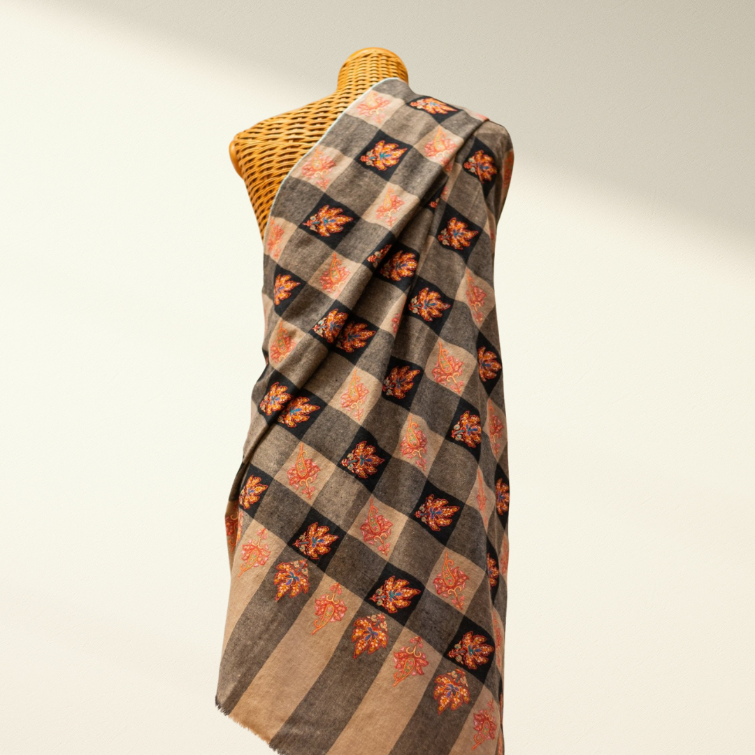 Plaid pashmina shawl with floral patterns draped over a mannequin against a neutral background
