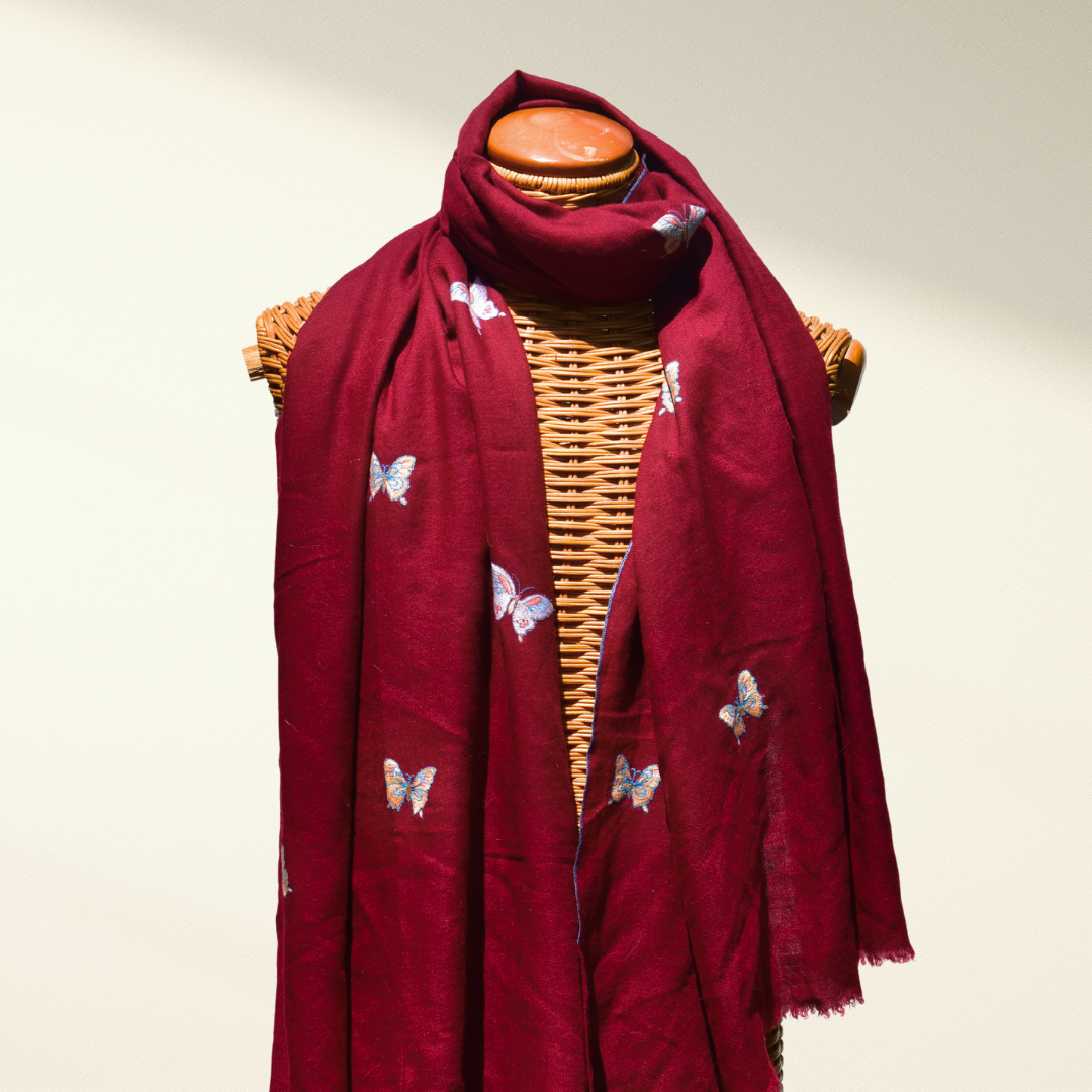Red pashmina shawl with butterfly patterns draped over a mannequin on a plain background