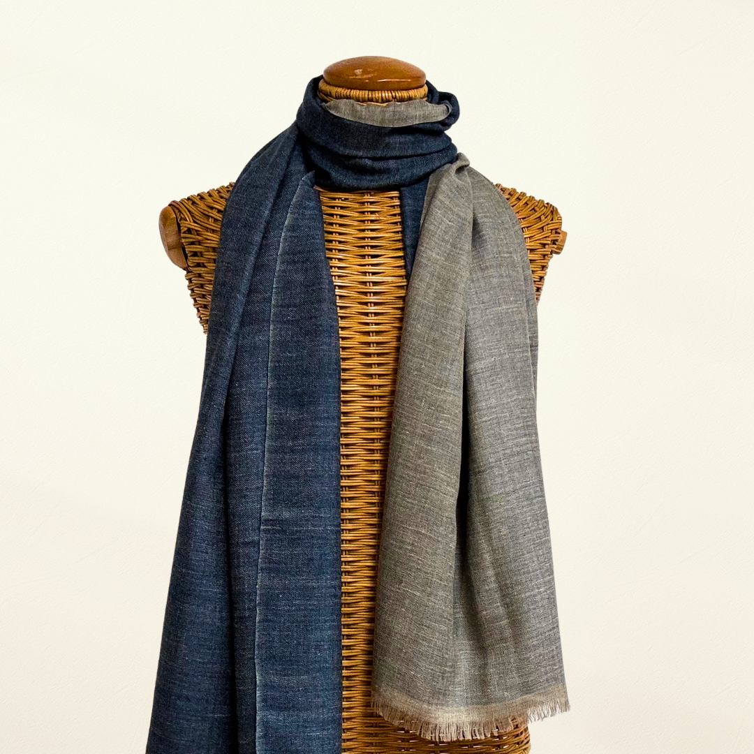 Reversible Scarf, one side blue and one side gray, draped over a wicker basket on a light background.