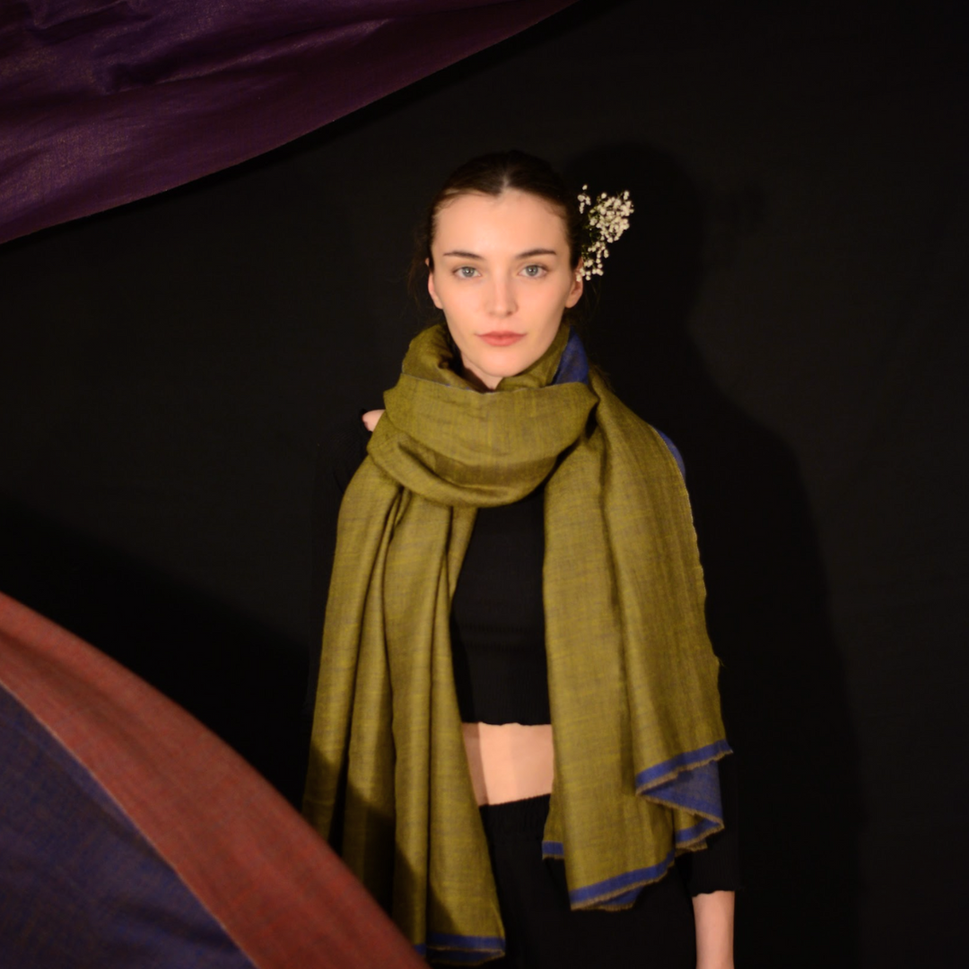 Woman wearing a green pashmina scarf with a dark background