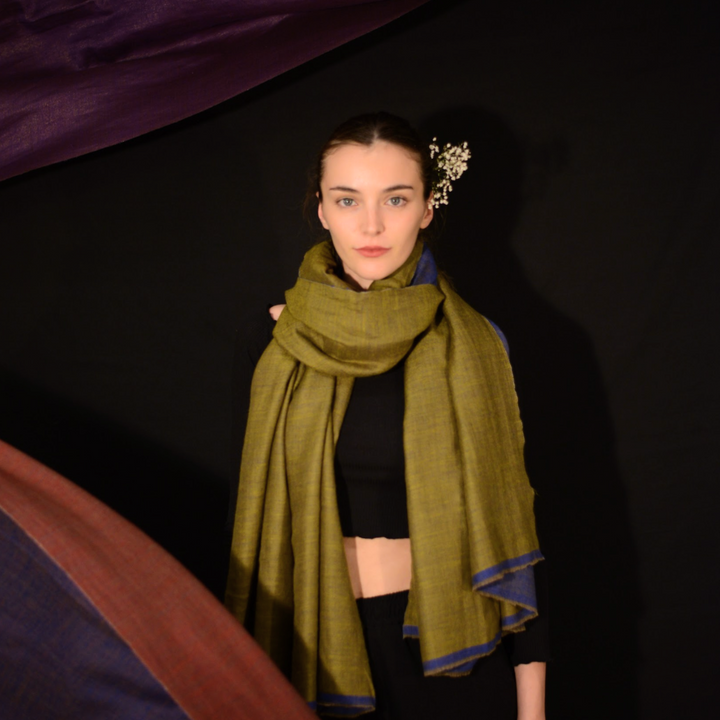 Woman wearing a green pashmina scarf with a dark background