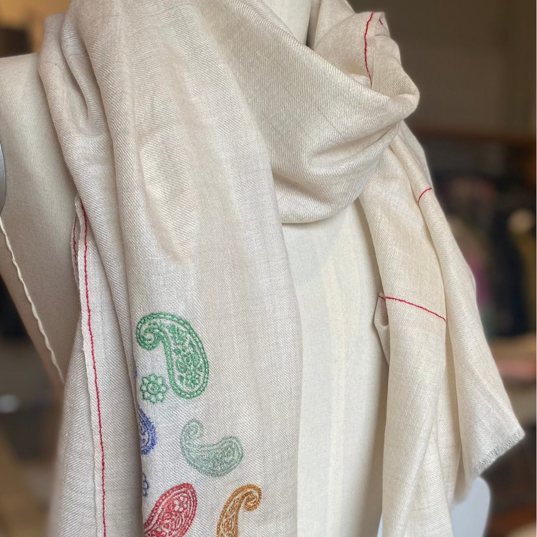 Soft ivory wrap featuring delicate hand-embroidered paisleys draped on mannequin