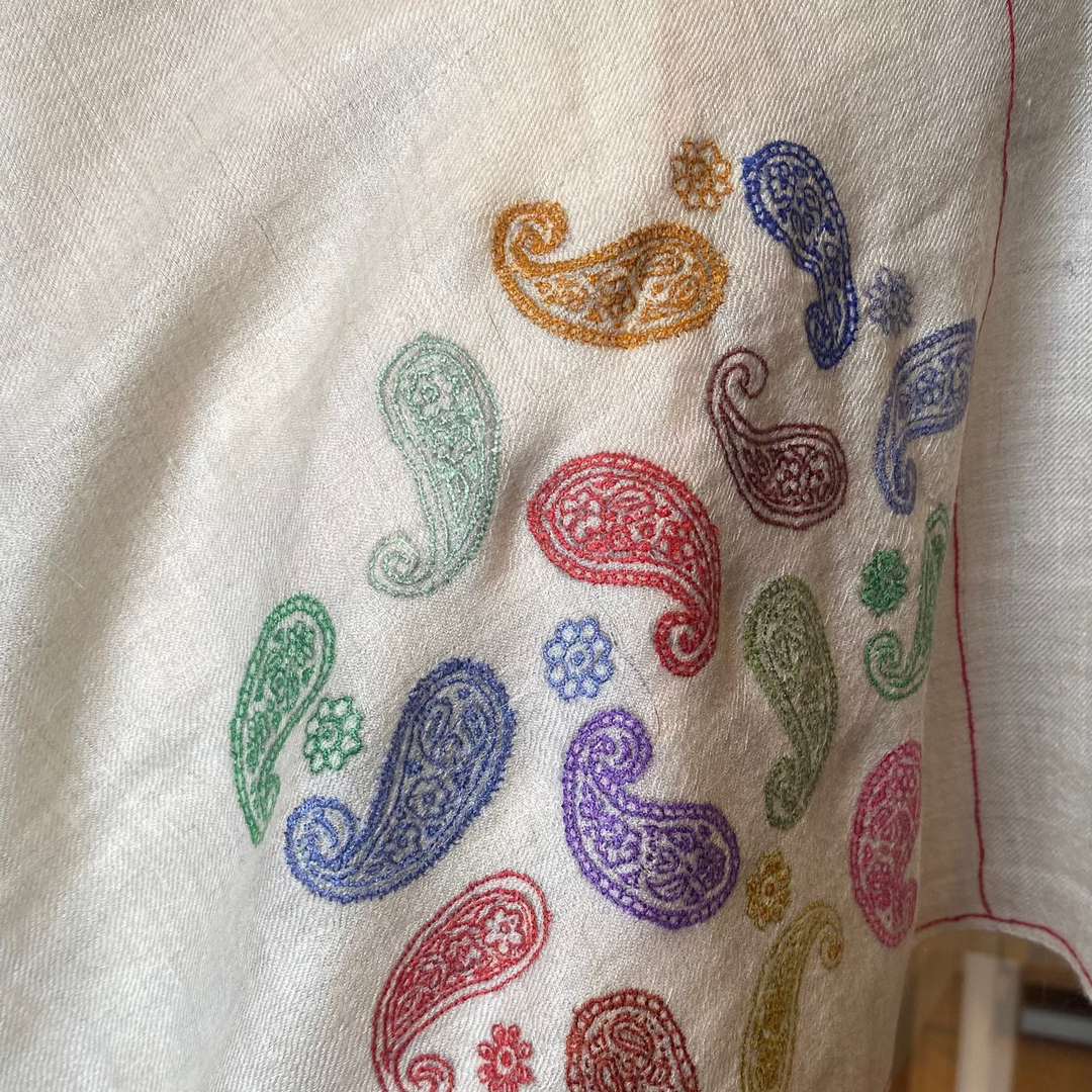 Soft ivory wrap featuring delicate hand-embroidered paisleys Closeup design