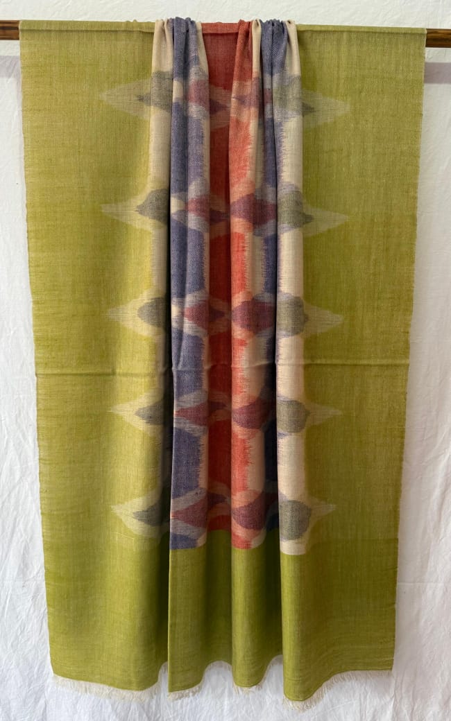 Pashmina Scarves with different Ikat patterns hanging on a rack against a white wall.