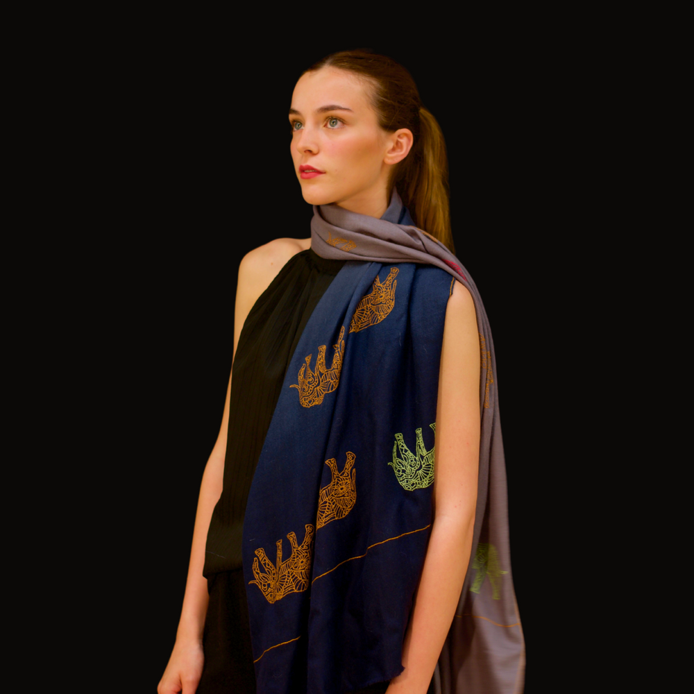 Woman wearing a dark blue pashmina shawl with elephant patterns on a black background