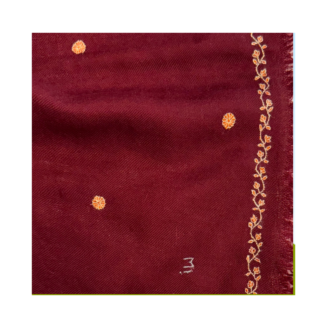 A close-up of a deep maroon afterglow foulard, featuring small orange floral motifs and a vertical border of orange floral embroidery along the fringed edge.