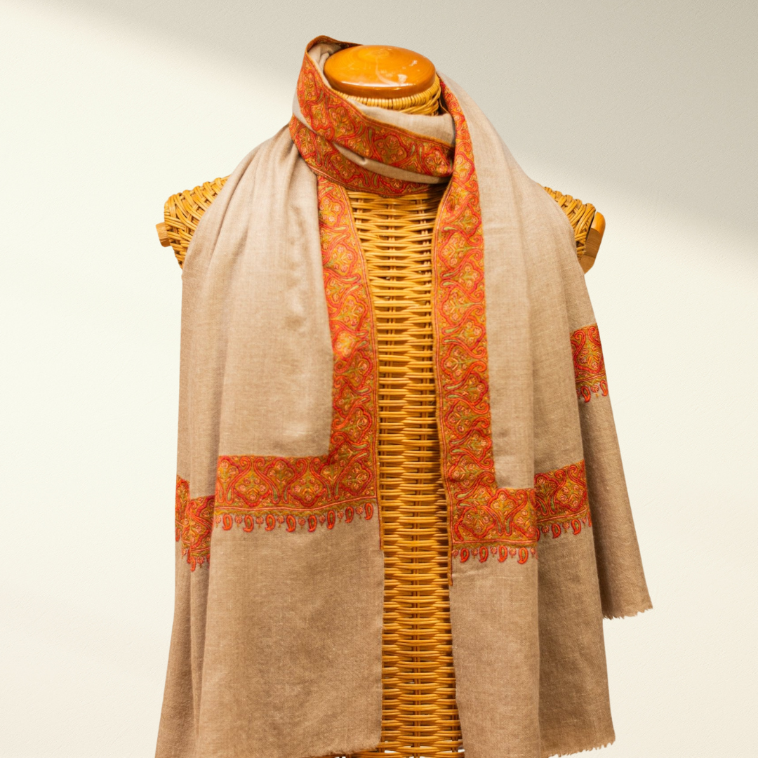 Mannequin wearing a beige and orange pashmina scarf on a mannequin with a light background