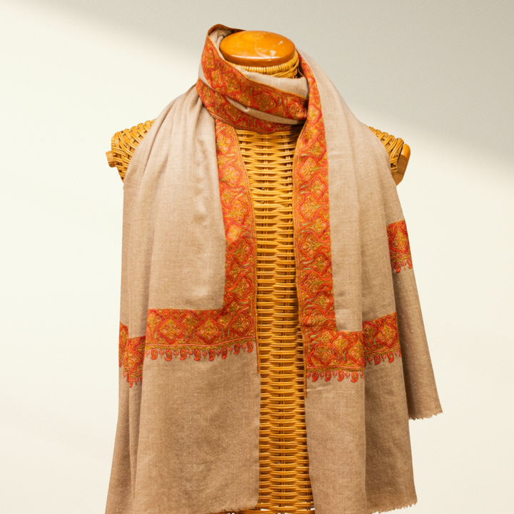 Mannequin wearing a beige and orange pashmina scarf on a mannequin with a light background