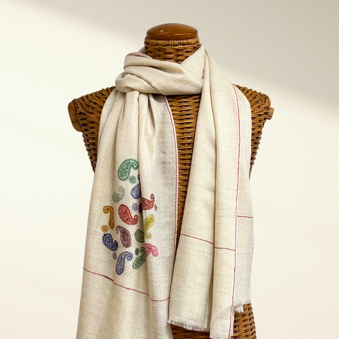 Mannequin wearing a beige pashmina scarf with colorful paisley patterns on a neutral background