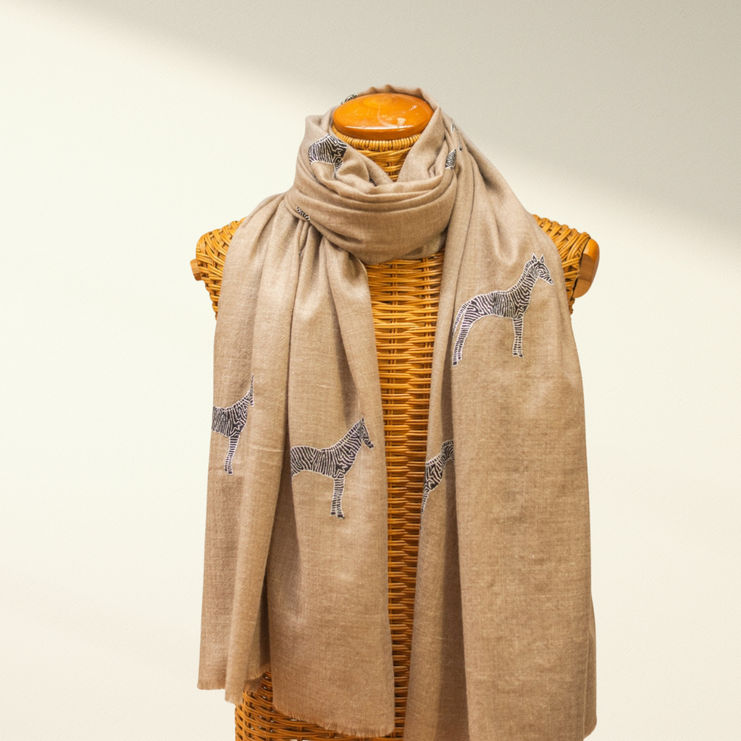 Beige cashmere scarf with zebra patterns on a mannequin against a beige background