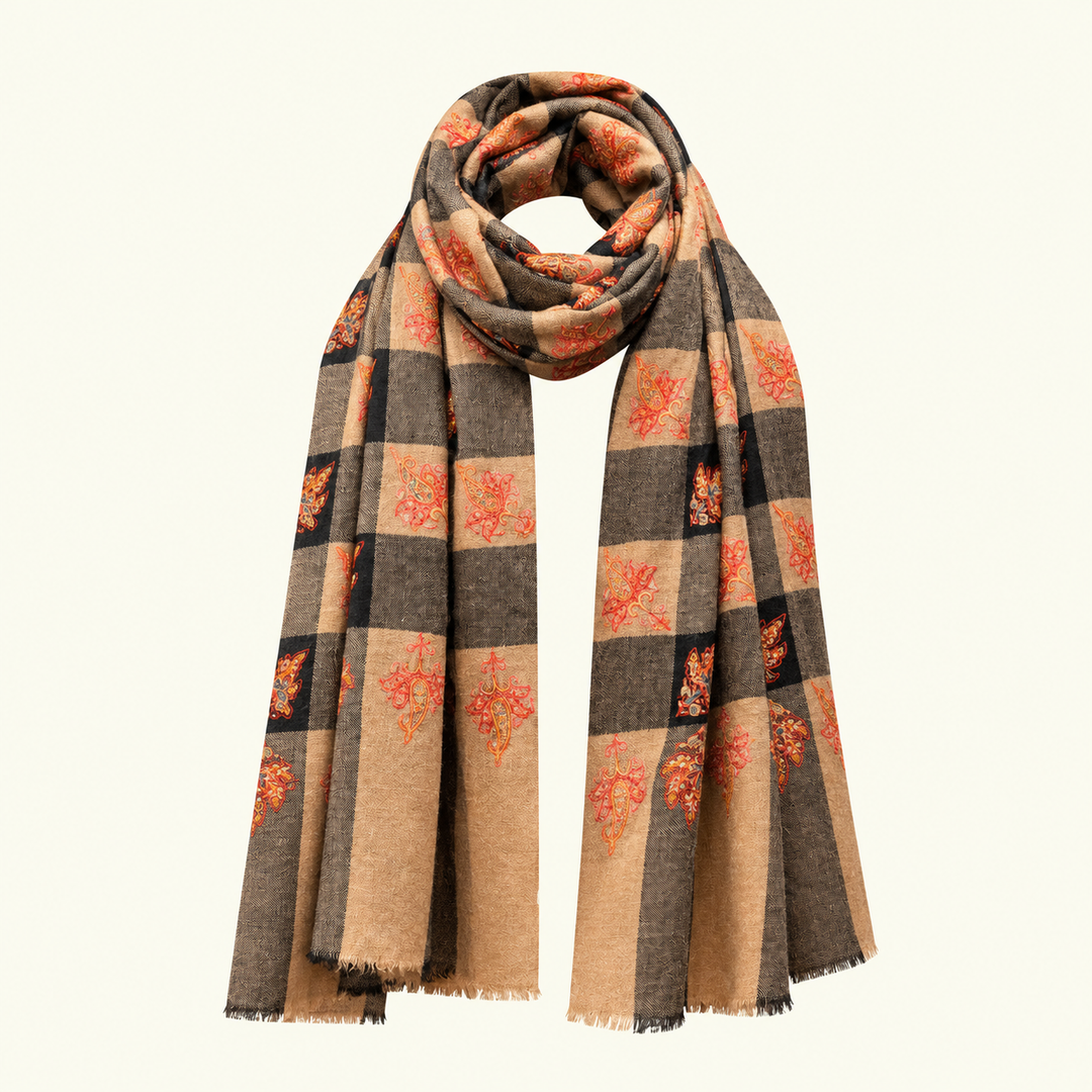 A long pashmina scarf with a checkered pattern in beige, dark brown, and black, decorated with orange and red autumn leaf motifs, shown on a solid off-white background.