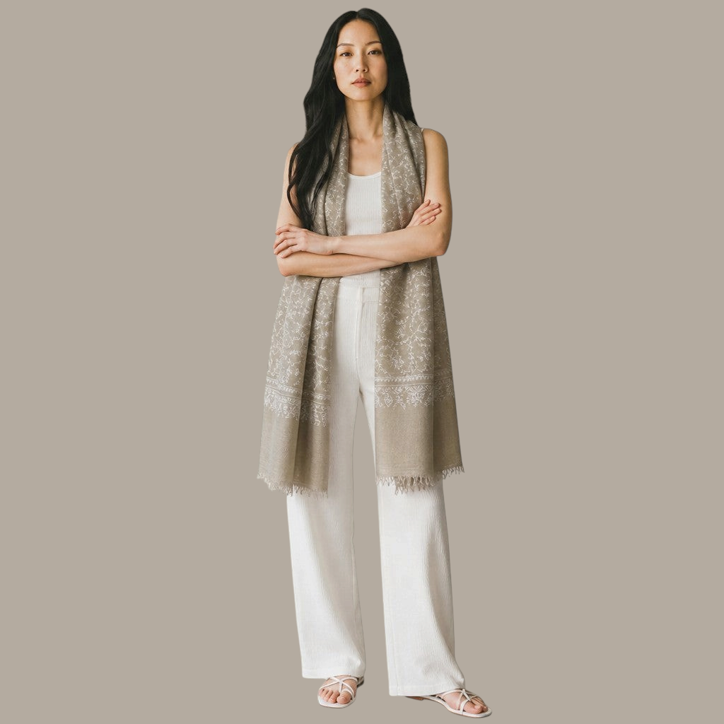 Indus Weavers taupe pashmina shawl with ivory Sozni floral embroidery worn by a woman in white clothing