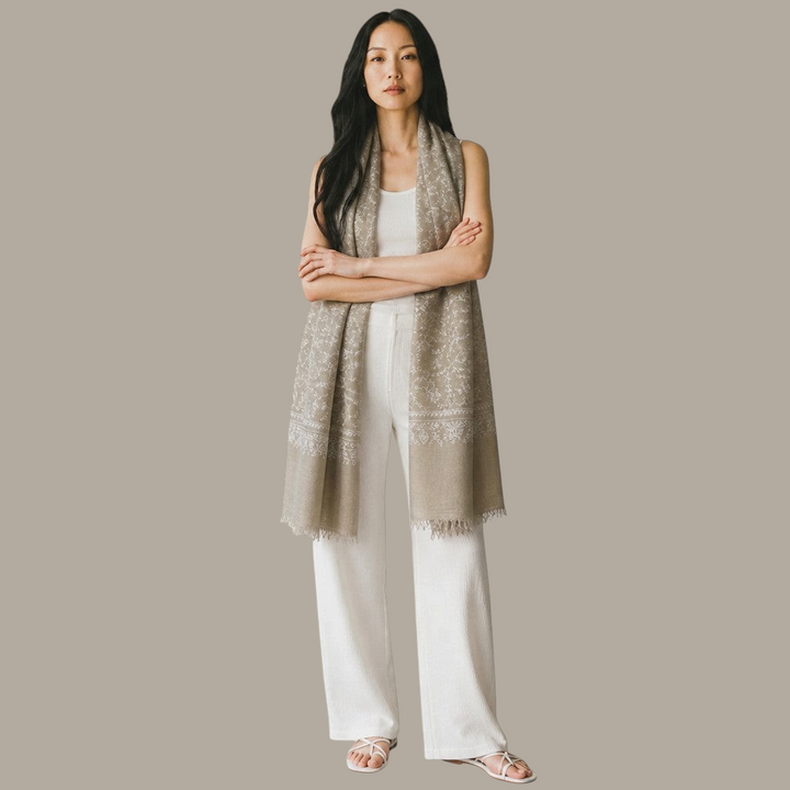 Indus Weavers taupe pashmina shawl with ivory Sozni floral embroidery worn by a woman in white clothing