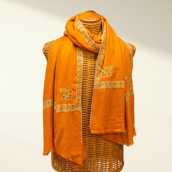 mustard pashmina scarf with intricate patterns draped over a mannequin on a plain background