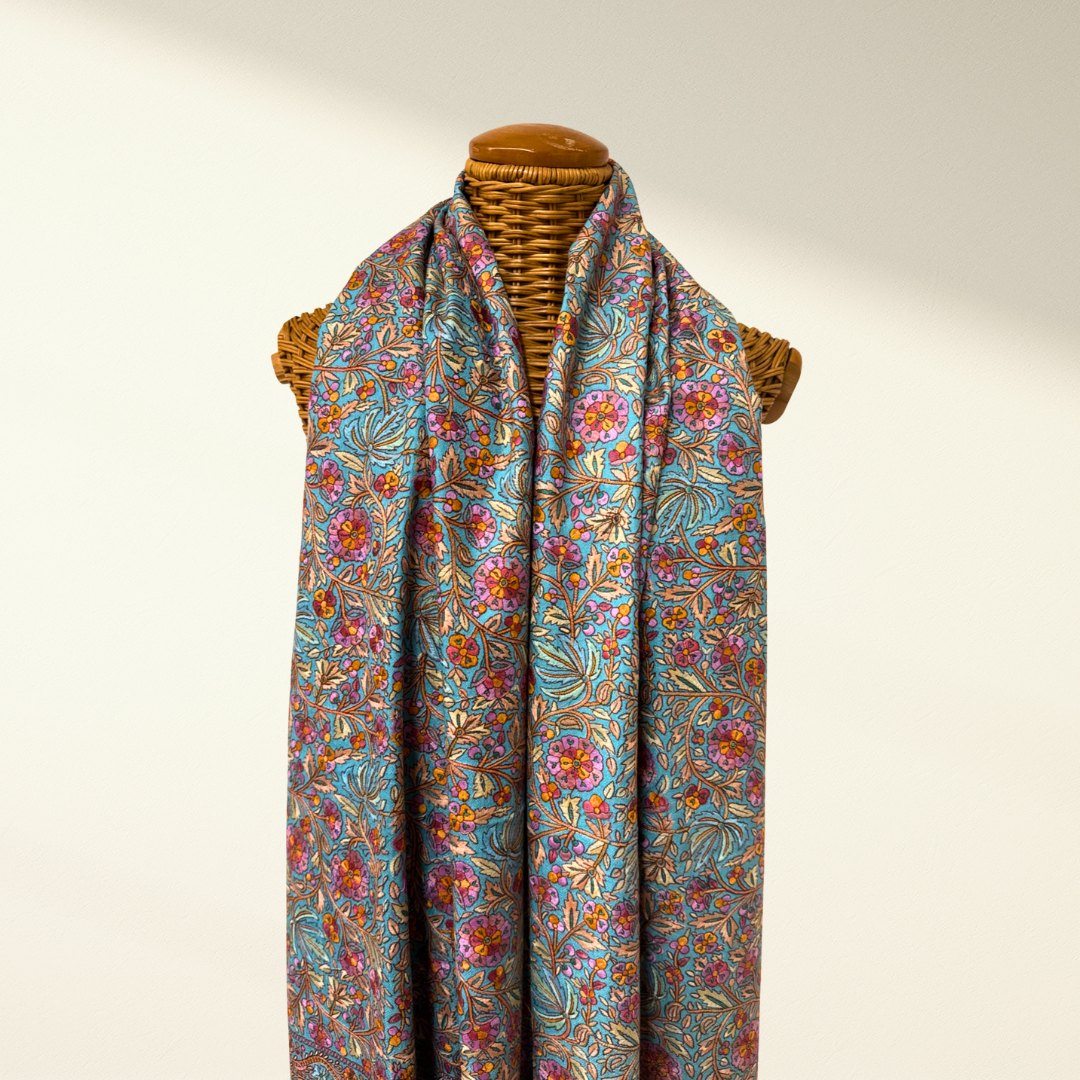 Colorful floral-patterned pashmina shawl bloom on a mannequin against a plain background