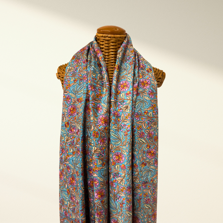 Colorful floral-patterned pashmina shawl bloom on a mannequin against a plain background