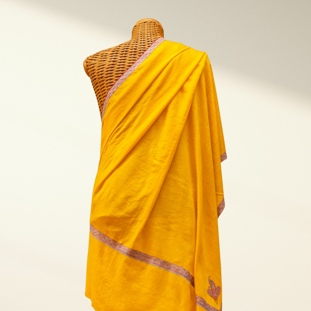 Yellow pashmina with border on a mannequin against a plain background