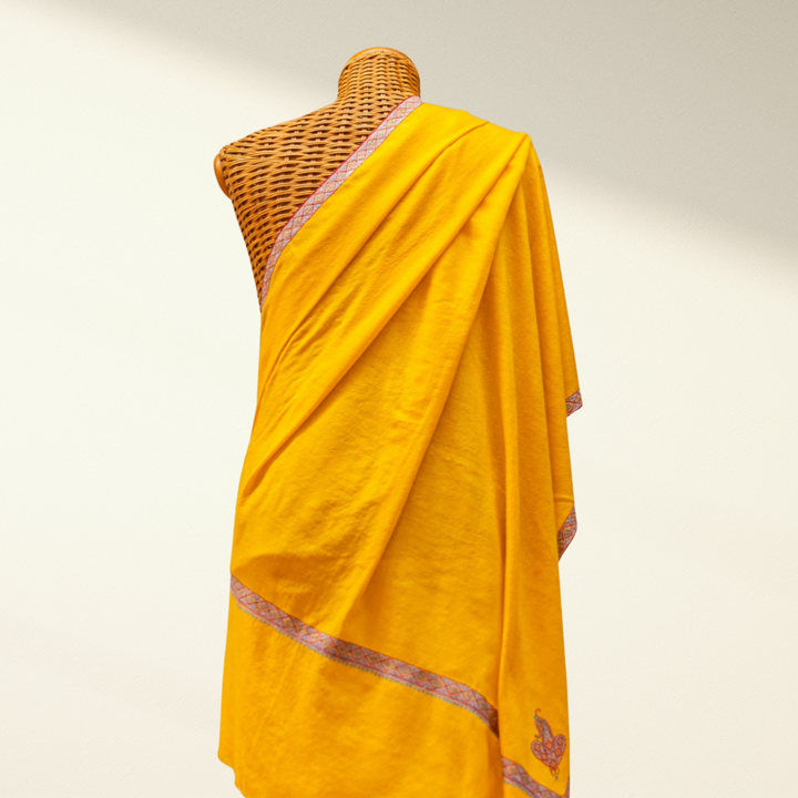 Yellow pashmina with border on a mannequin against a plain background